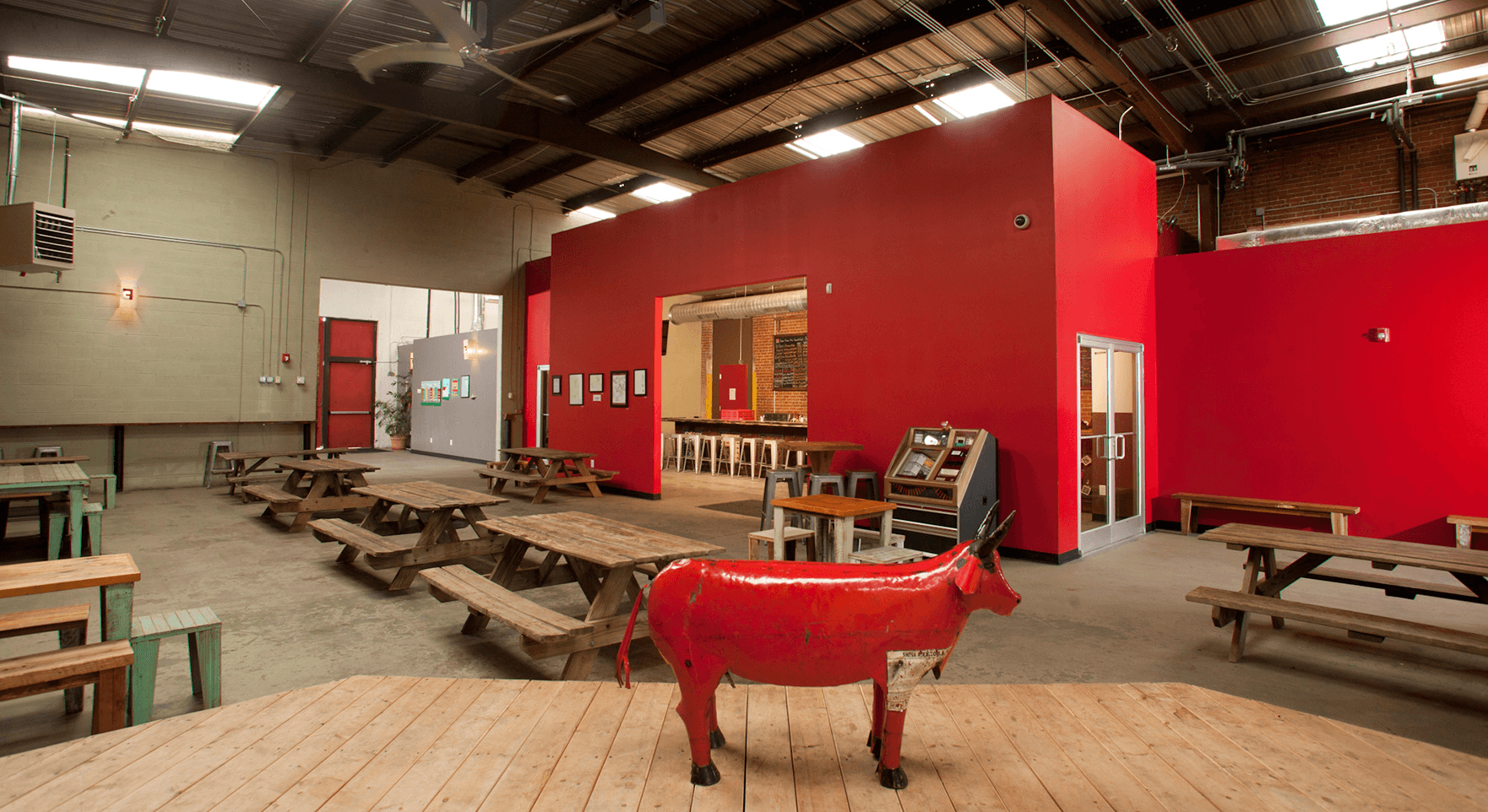 a red cow is standing in a large room with tables and chairs